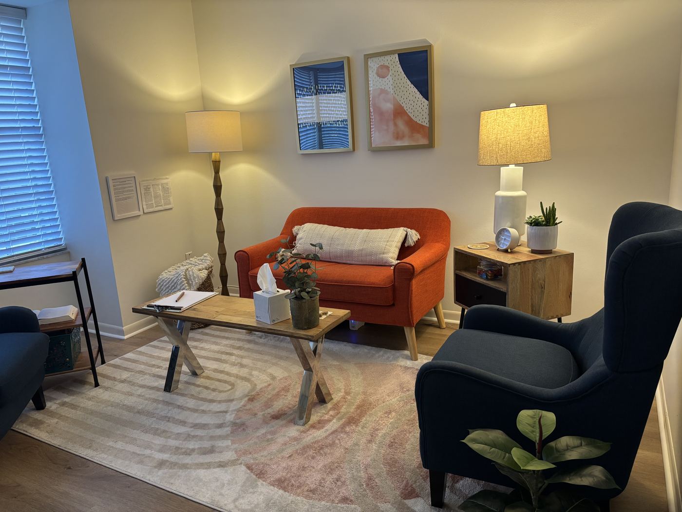 Therapy office seating area with orange loveseat and navy accent chairs